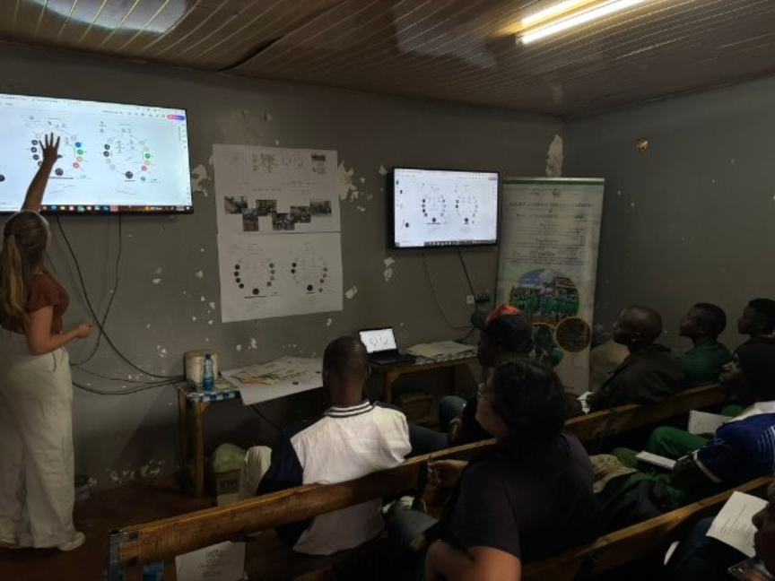 A group of people sitting in a room with a screen on the wall

AI-generated content may be incorrect.